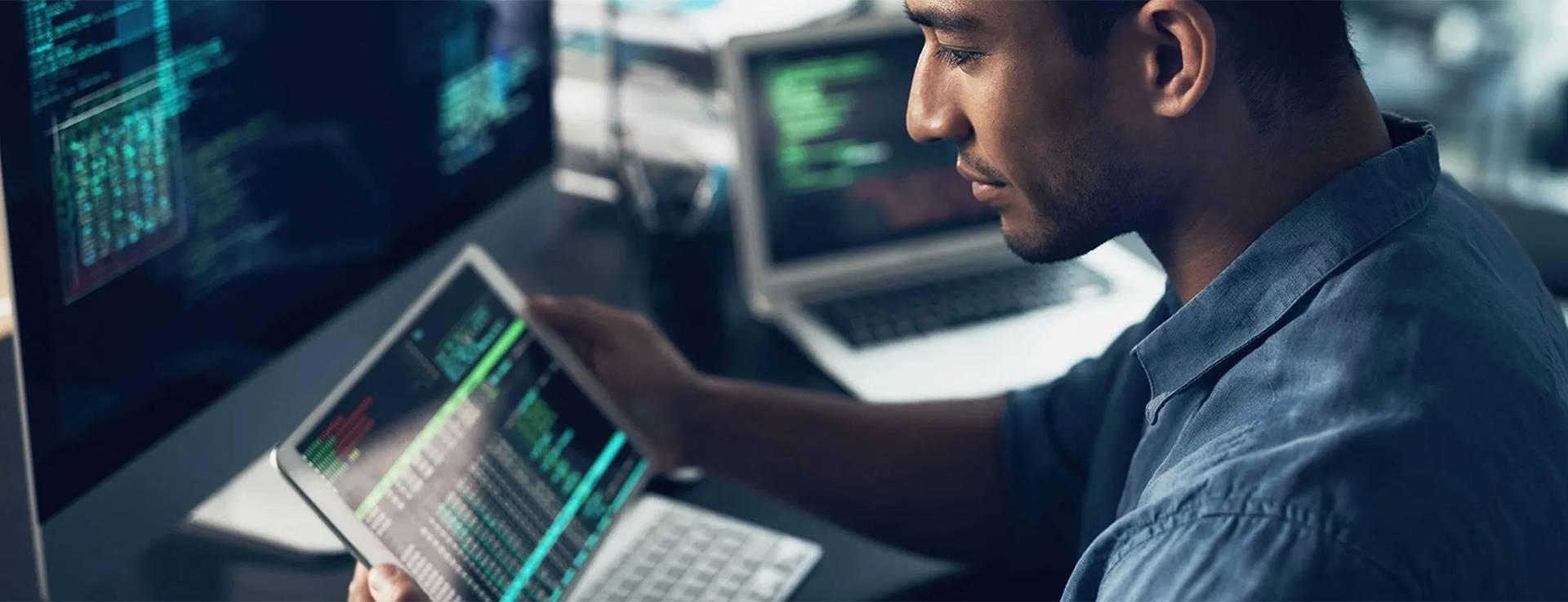 man sitting infront on computer holding an ipad.